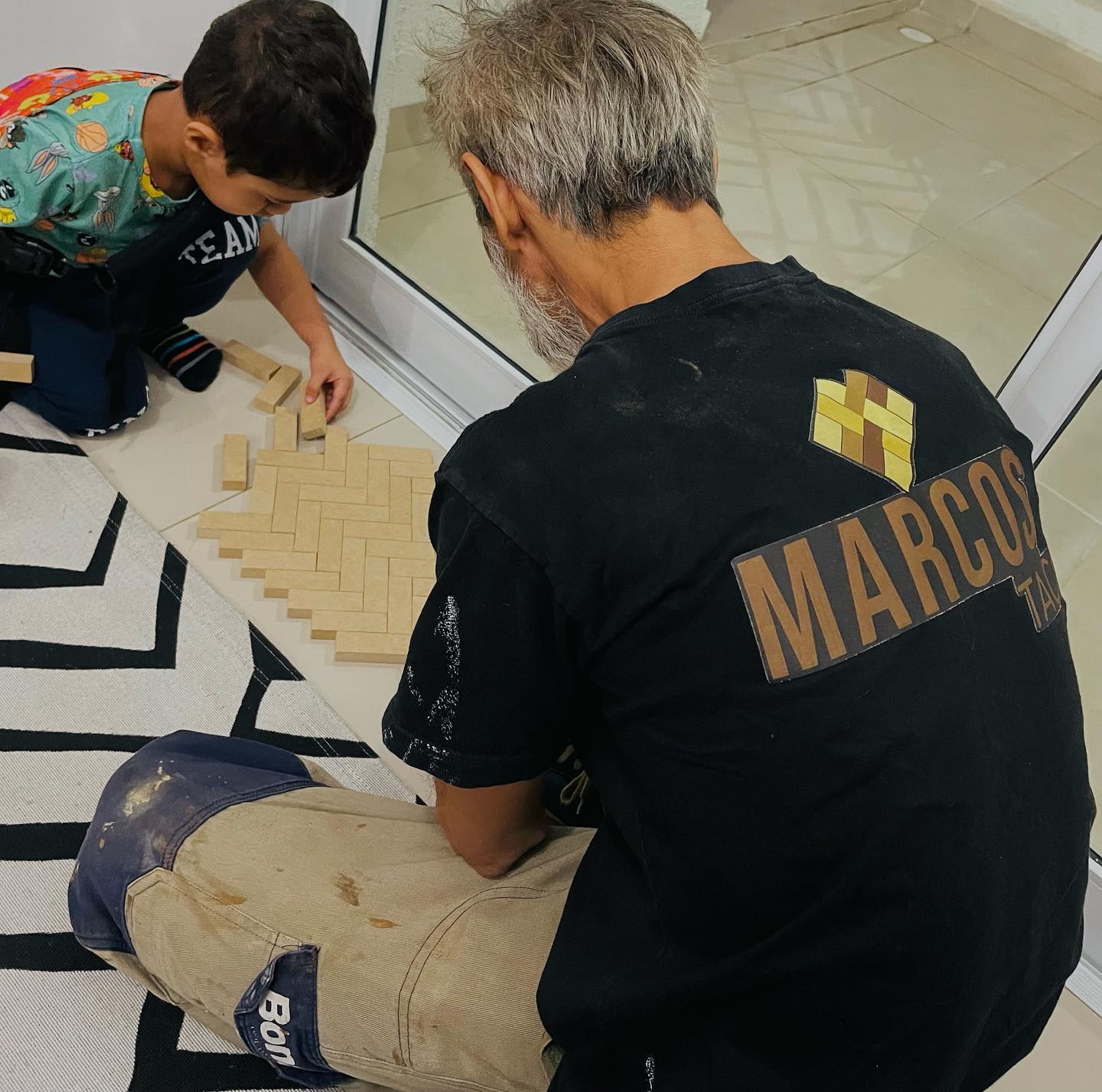Profissional com a camiseta da Marcos Taco montando tacos em espinha de peixe com uma criança